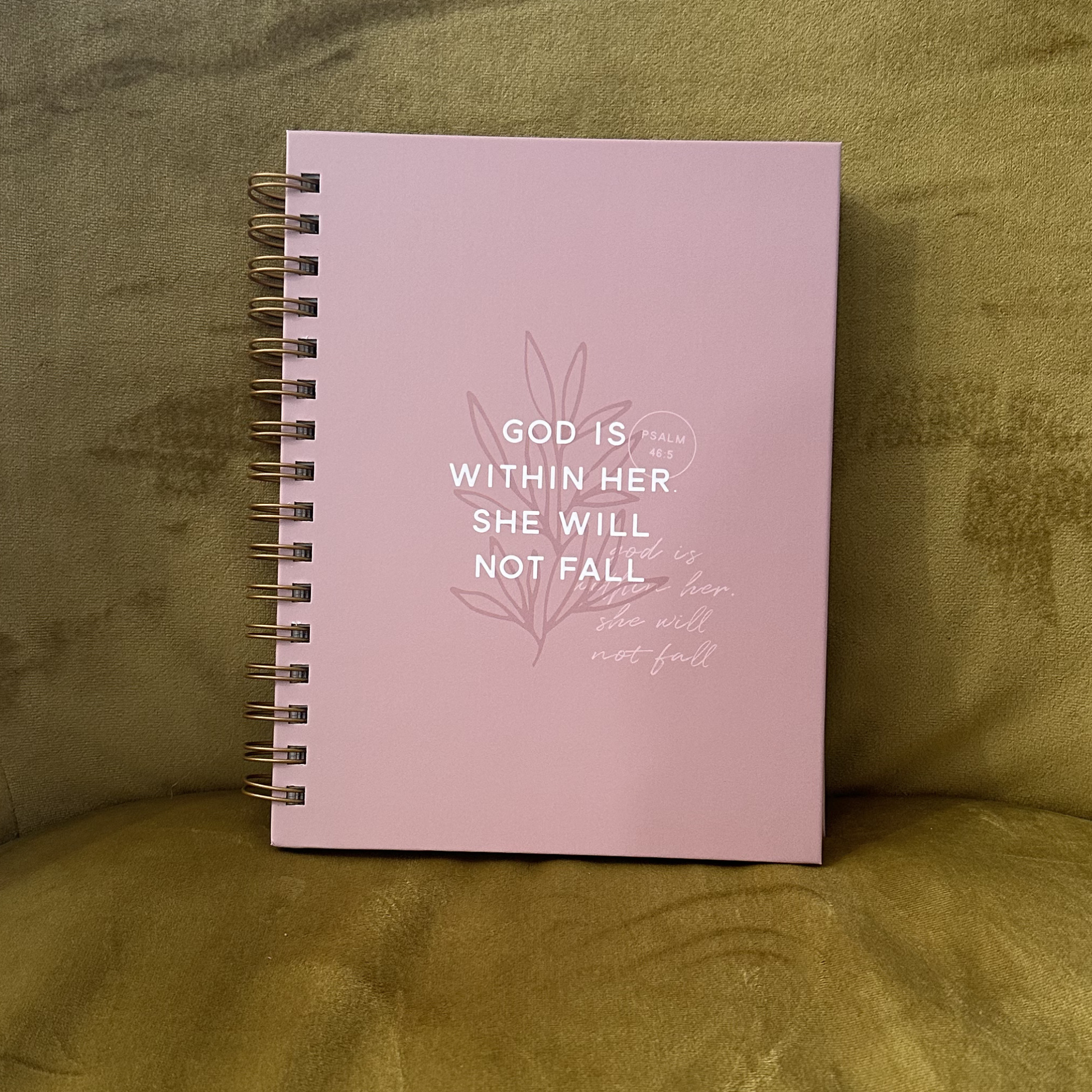 Pink notebook with motivational quote on a green fabric background
